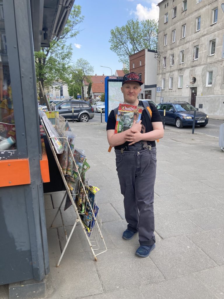 mężczyzna stoi przed kioskiem z gazetą w ręce
